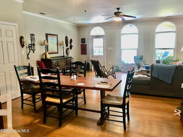 dining space featuring light wood-type flooring, visible vents, ornamental molding, and ceiling fan