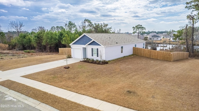 ranch-style home with a garage, concrete driveway, a water view, and fence