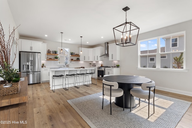 dining area with plenty of natural light, sink, an inviting chandelier, and light wood-type flooring