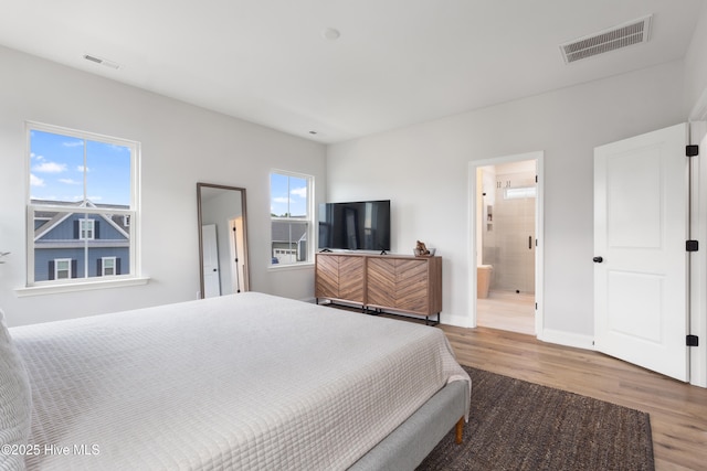 bedroom with hardwood / wood-style floors and ensuite bathroom