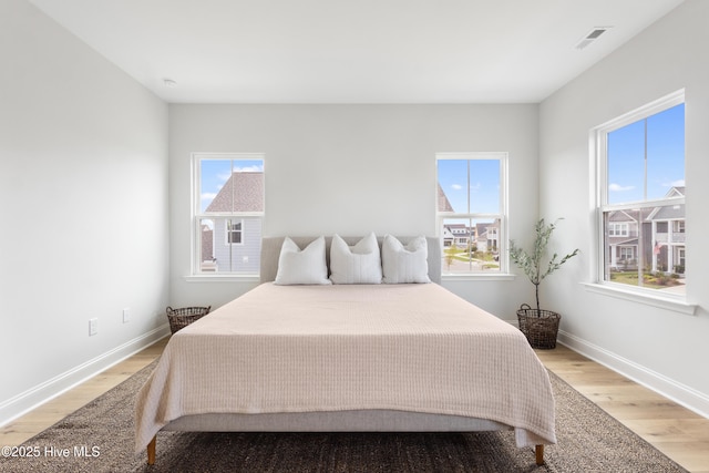 bedroom featuring multiple windows and light hardwood / wood-style flooring