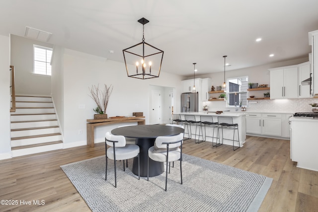 dining area with an inviting chandelier, a wealth of natural light, and light hardwood / wood-style floors