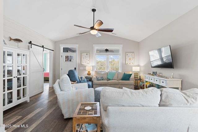 living room featuring dark hardwood / wood-style floors, ceiling fan, a barn door, and vaulted ceiling