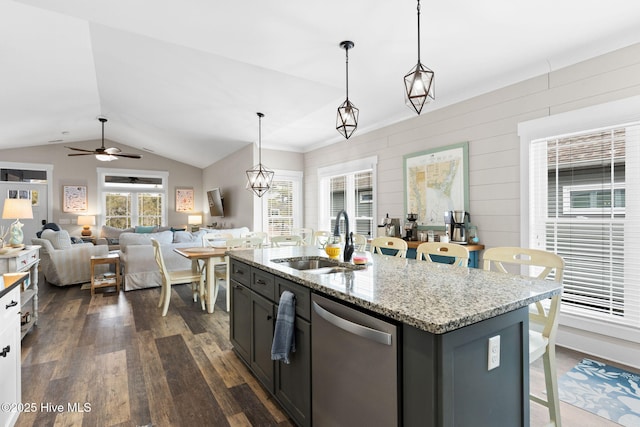 kitchen with sink, hanging light fixtures, light stone countertops, an island with sink, and stainless steel dishwasher