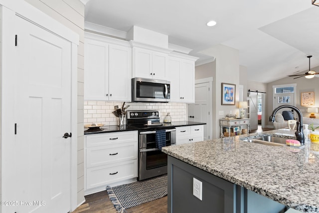 kitchen featuring a barn door, white cabinetry, appliances with stainless steel finishes, and sink