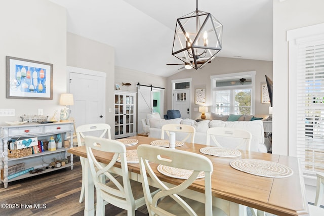 dining room with vaulted ceiling, a barn door, dark hardwood / wood-style floors, and an inviting chandelier