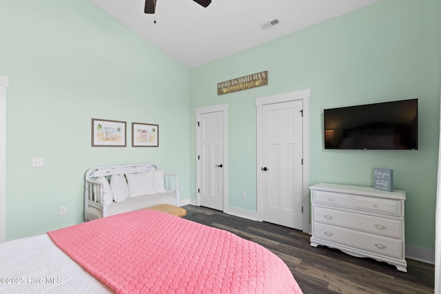 bedroom featuring ceiling fan, dark wood-type flooring, and multiple closets