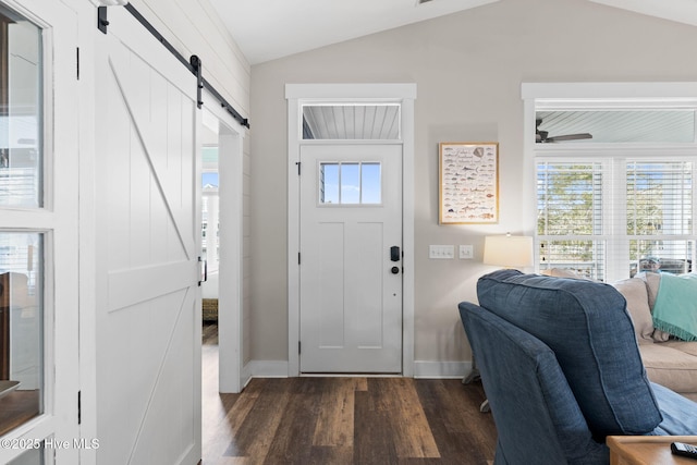 foyer entrance with dark wood-type flooring, ceiling fan, a barn door, and vaulted ceiling