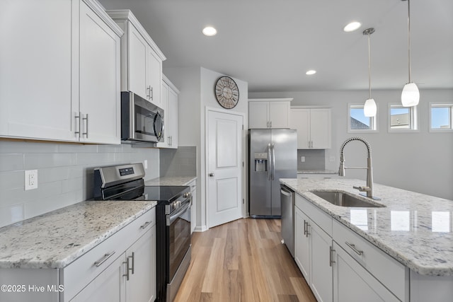 kitchen with stainless steel appliances, hanging light fixtures, sink, and white cabinets