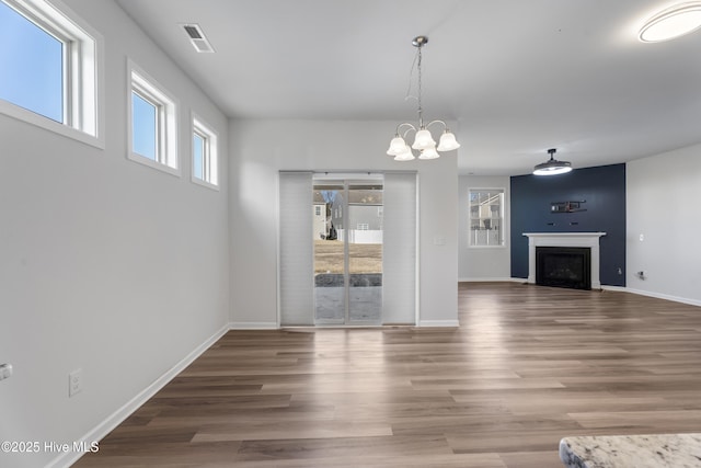 unfurnished living room with wood-type flooring and a notable chandelier