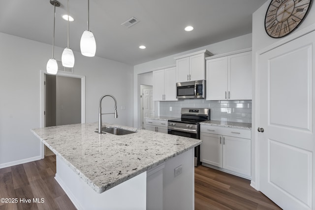 kitchen with sink, appliances with stainless steel finishes, white cabinetry, hanging light fixtures, and a center island with sink