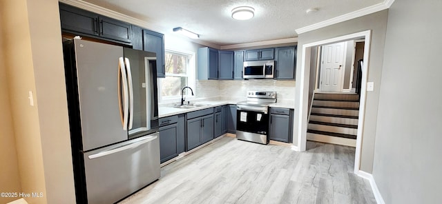 kitchen featuring sink, crown molding, tasteful backsplash, appliances with stainless steel finishes, and light hardwood / wood-style floors