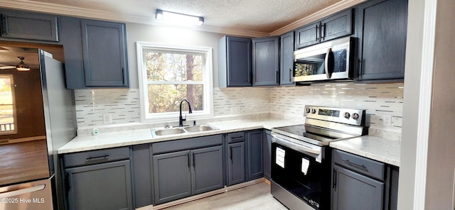 kitchen featuring sink, crown molding, stainless steel appliances, tasteful backsplash, and a textured ceiling