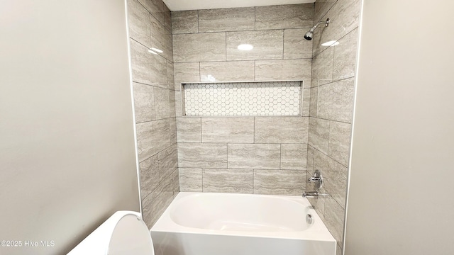 bathroom with tiled shower / bath combo and toilet