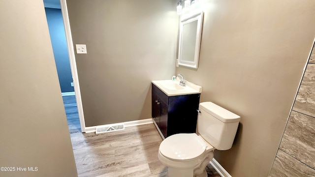 bathroom with wood-type flooring, toilet, and vanity