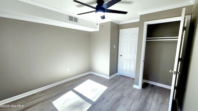 unfurnished bedroom featuring ornamental molding, ceiling fan, light hardwood / wood-style floors, and a closet