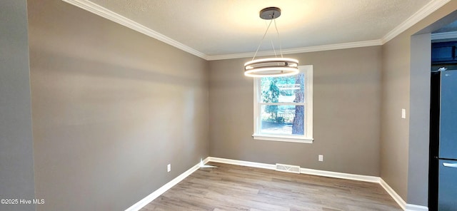 unfurnished dining area with hardwood / wood-style floors and crown molding