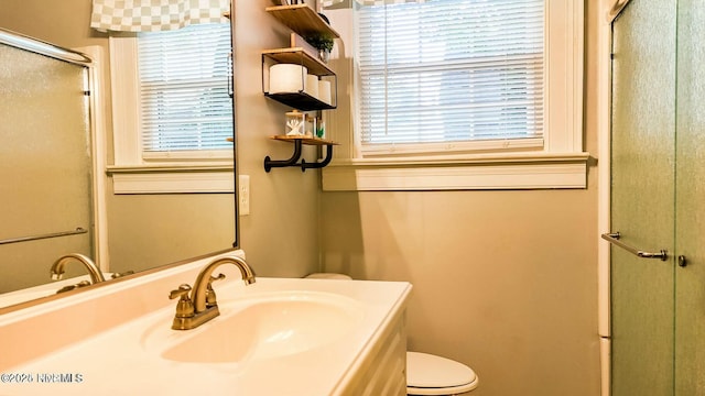 bathroom with a shower with door, vanity, and toilet