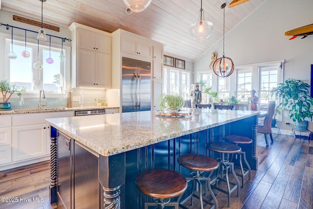 kitchen featuring white cabinetry, dark hardwood / wood-style flooring, a kitchen island, pendant lighting, and stainless steel appliances