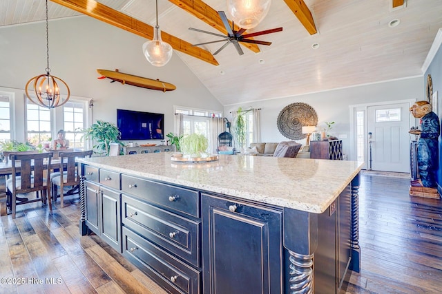 kitchen with light stone countertops, dark hardwood / wood-style floors, a center island, and hanging light fixtures