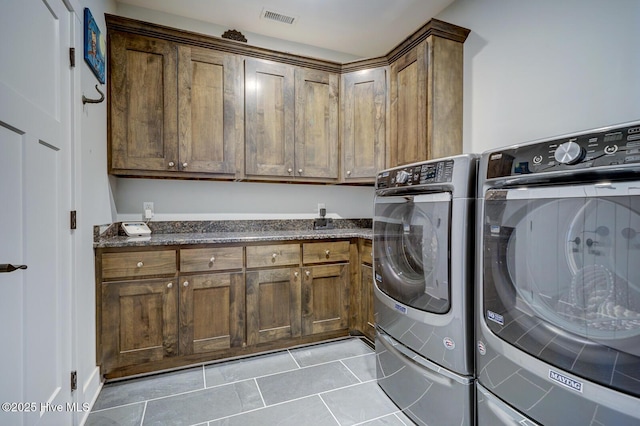 laundry area featuring light tile patterned flooring, cabinets, and washing machine and clothes dryer