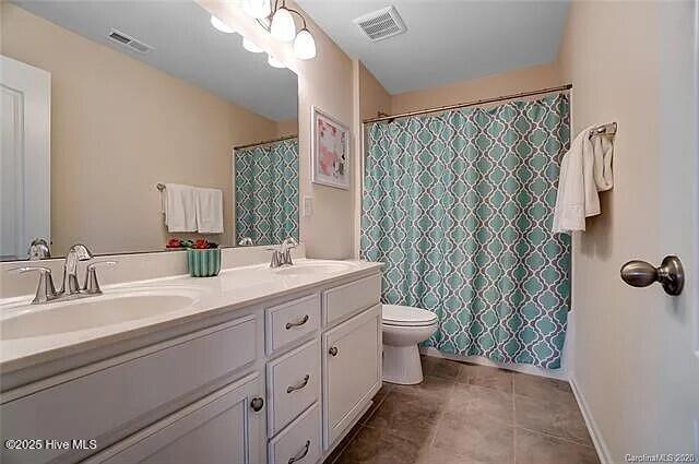 full bathroom with visible vents, a sink, and double vanity