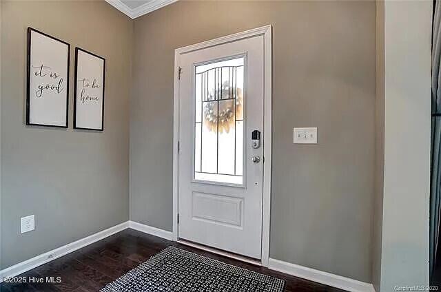 doorway with baseboards, dark wood finished floors, and ornamental molding