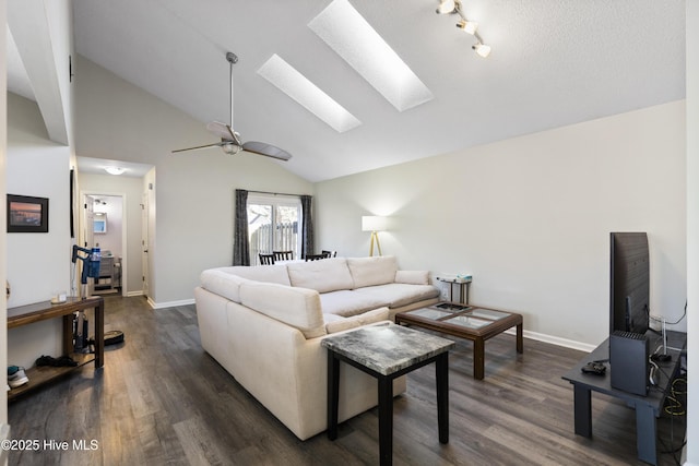 living room featuring high vaulted ceiling, dark hardwood / wood-style floors, ceiling fan, and a skylight