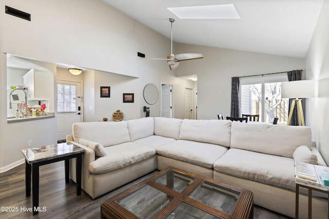 living room featuring a skylight, dark wood-type flooring, plenty of natural light, and ceiling fan