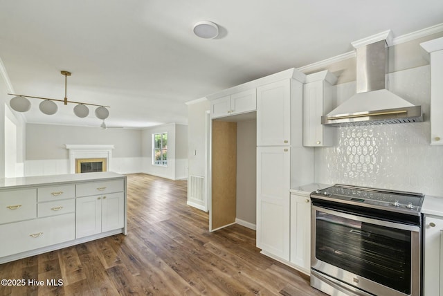 kitchen featuring white cabinetry, ornamental molding, wall chimney exhaust hood, and stainless steel electric range oven