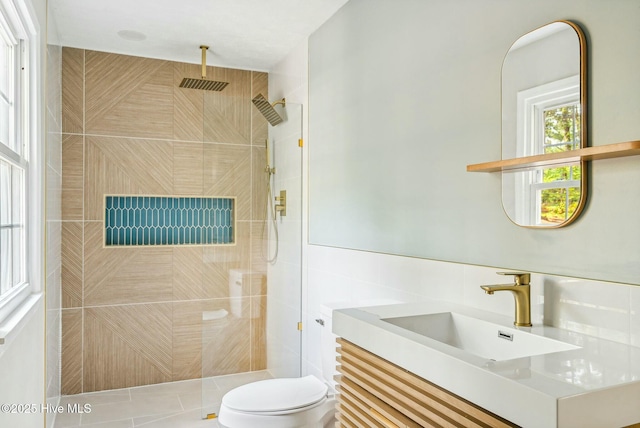 bathroom featuring vanity, a tile shower, and toilet