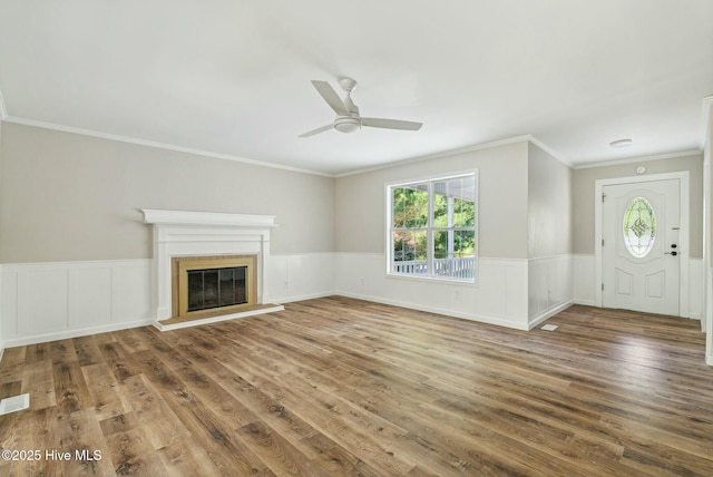 unfurnished living room featuring dark hardwood / wood-style flooring, ornamental molding, and ceiling fan