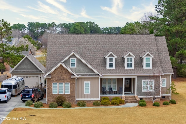 view of front of home featuring board and batten siding, a front lawn, concrete driveway, roof with shingles, and covered porch