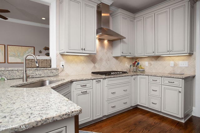 kitchen featuring light stone counters, ornamental molding, a sink, stainless steel gas stovetop, and wall chimney exhaust hood