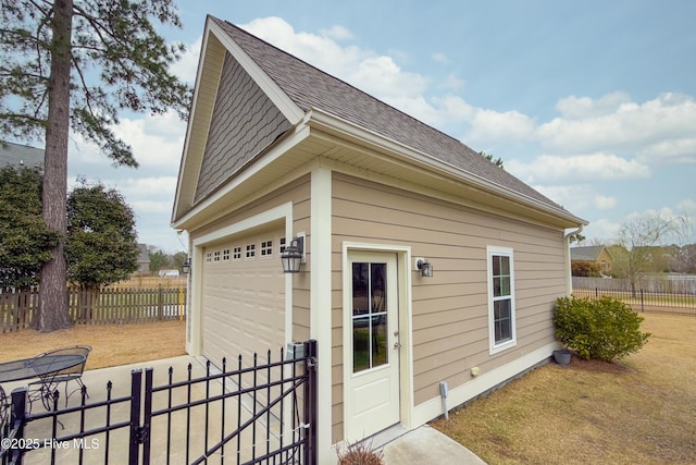 view of side of home with an outdoor structure, fence, a garage, and driveway