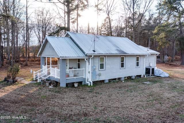 back house at dusk featuring covered porch and central air condition unit