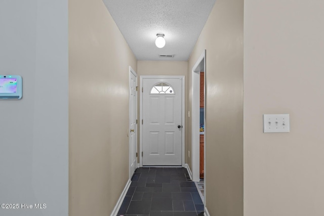 doorway to outside with a textured ceiling