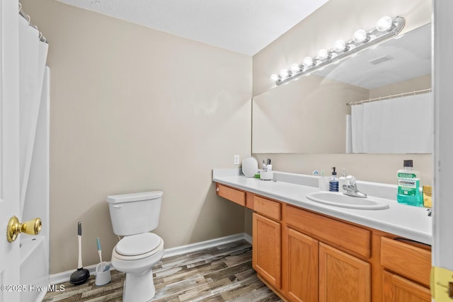 bathroom with hardwood / wood-style flooring, vanity, toilet, and curtained shower