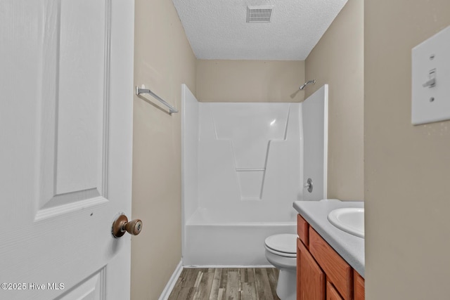 full bathroom featuring toilet, wood-type flooring, tub / shower combination, a textured ceiling, and vanity