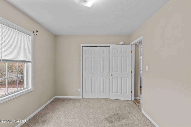 unfurnished bedroom featuring carpet floors, a textured ceiling, and a closet