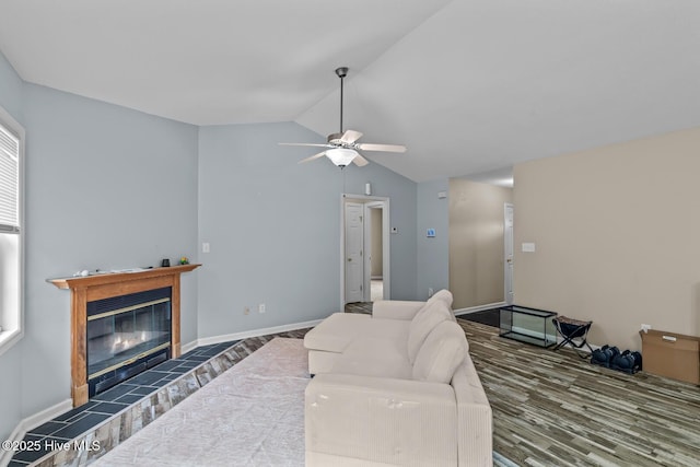 living room with dark hardwood / wood-style flooring, lofted ceiling, ceiling fan, and a fireplace