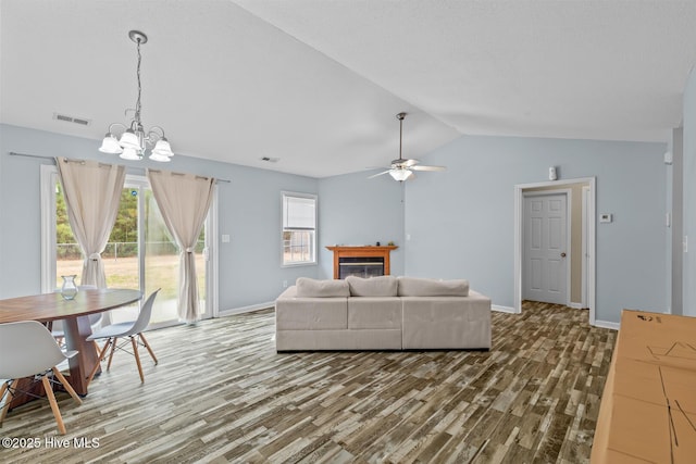 living room featuring vaulted ceiling, ceiling fan with notable chandelier, and hardwood / wood-style floors