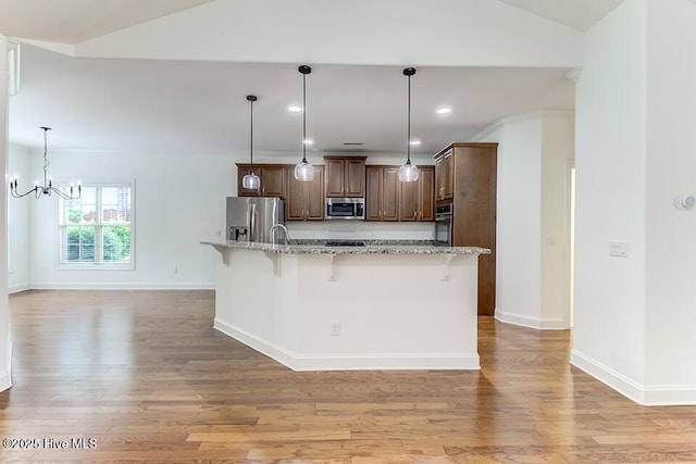 2173 Palm Pointe NE, Leland, NC 28451 - kitchen featuring appliances with stainless steel finishes, a kitchen bar, vaulted ceiling, light wood-type flooring, and a chandelier