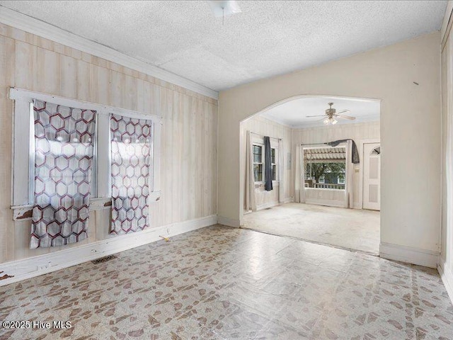 empty room with crown molding, ceiling fan, and a textured ceiling