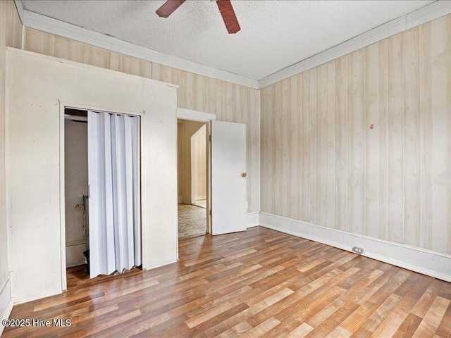 unfurnished bedroom with crown molding, ceiling fan, hardwood / wood-style floors, a textured ceiling, and a closet