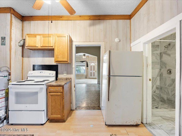 kitchen featuring ceiling fan, wooden walls, white appliances, and light hardwood / wood-style floors