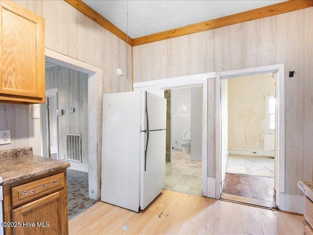 kitchen with white fridge, wood walls, and light hardwood / wood-style flooring