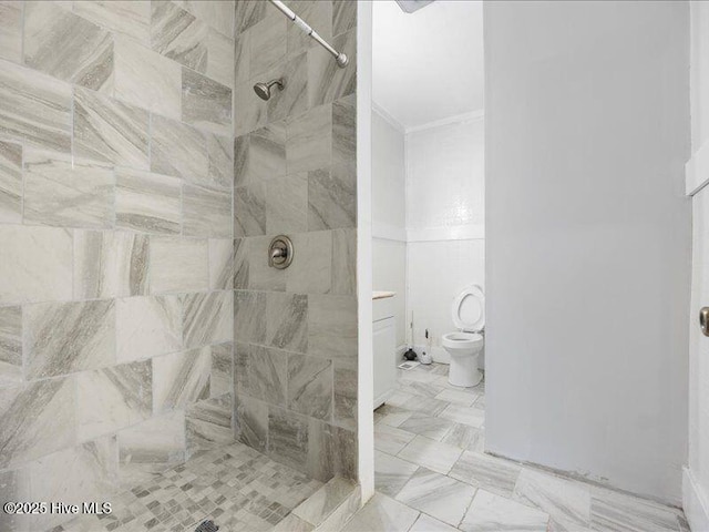 bathroom featuring crown molding, toilet, and tiled shower