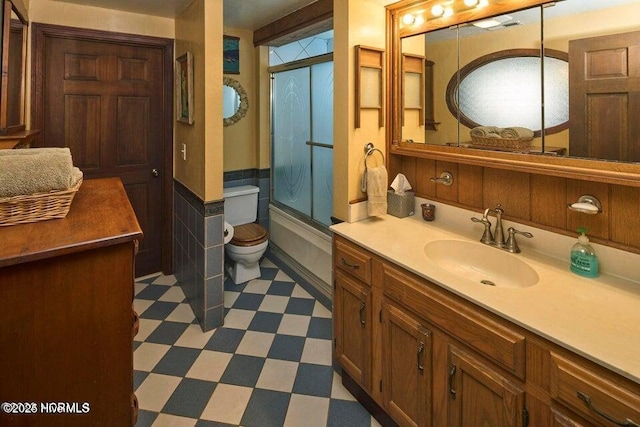 full bathroom featuring vanity, shower / bath combination with glass door, and toilet