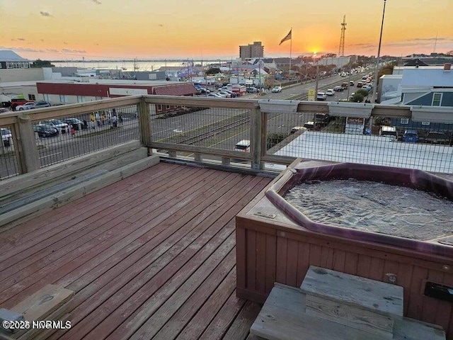 deck at dusk with an outdoor hot tub